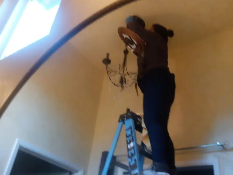 Electrician installing a chandelier in a Rolling Hills Estates residence